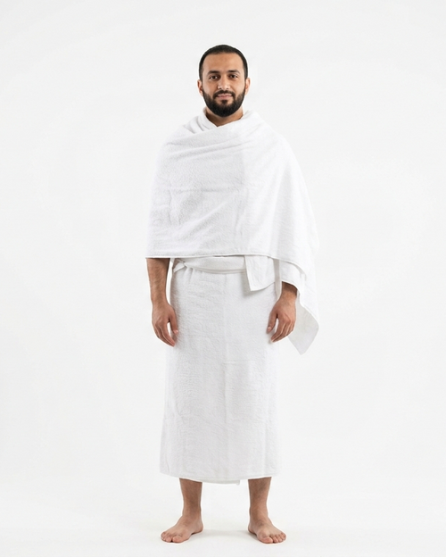 A man standing against a plain white studio background, wearing a white robe with a shawl draped over his shoulders.