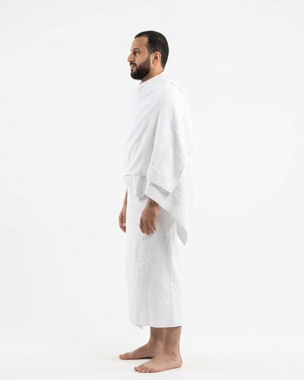 A man standing in profile wearing a white robe against a plain white studio background.